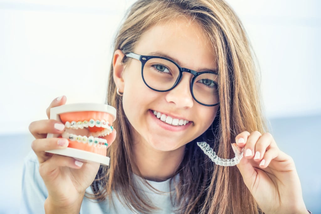 Mädchen vergleicht Aligner mit feste Zahnspangen