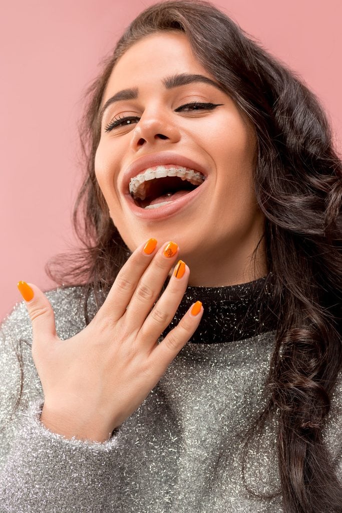 Frau mit Zahnspangen zur Behandlung eines Überbisses lacht
