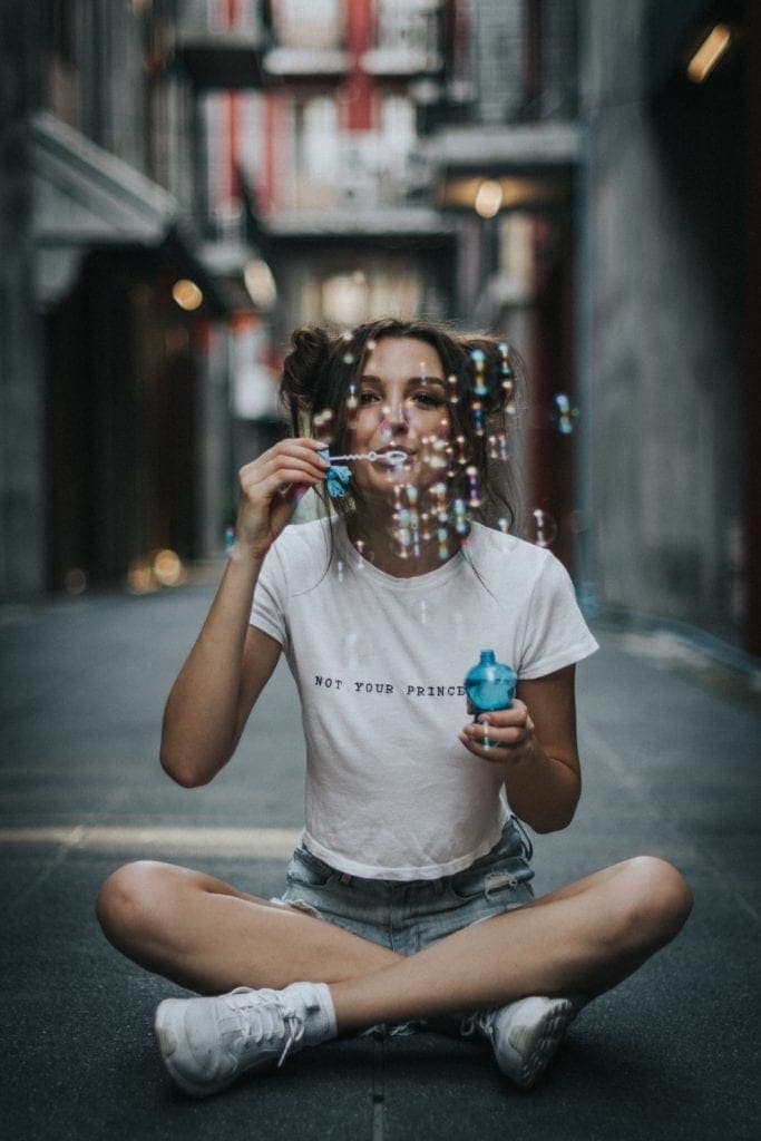 Eine Frau sitzt auf der Straße und macht Seifenblasen